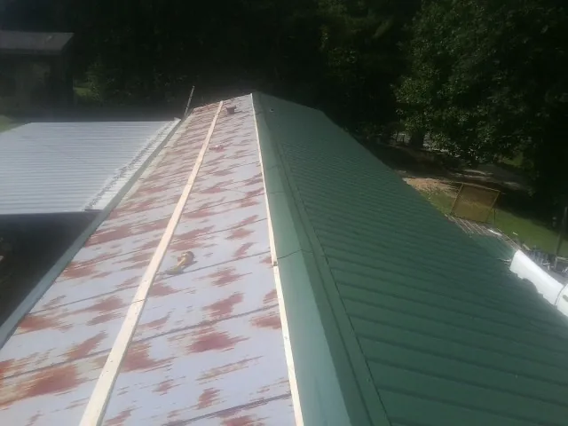 Old rusted panels beside newly installed green metal roofing — Wind Damage Roof Repair by Roofing Brothers in Wayland