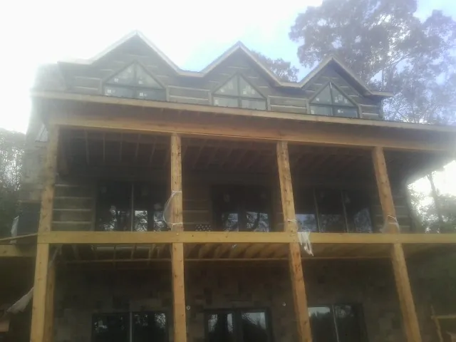 Dormers and porch framing on a large log home under construction — Roof Coating work by our crew in Wayland