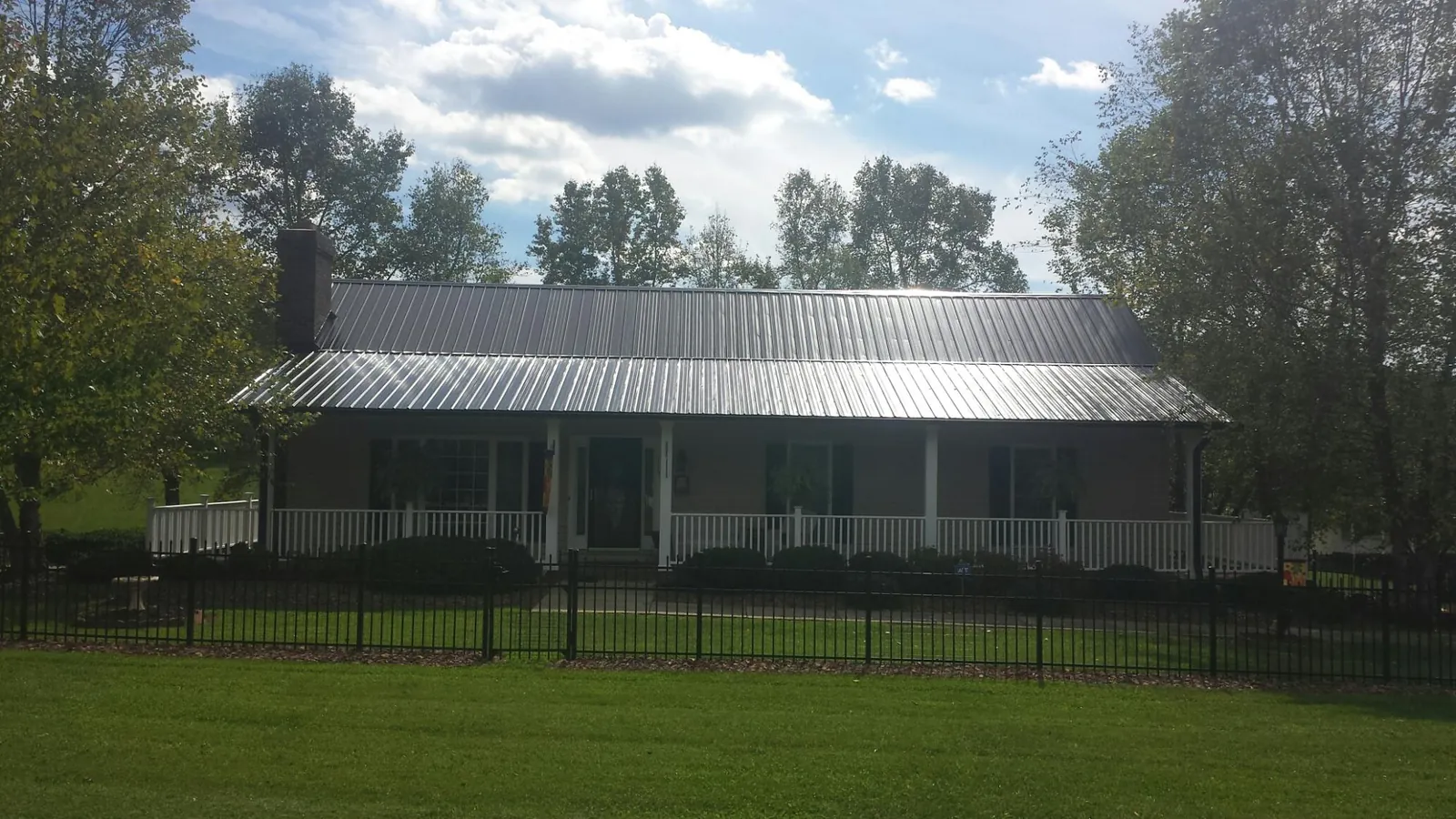 Gray metal roof on a brick ranch with a full width front porch — Gutter Guard Installation work by our crew in Wayland